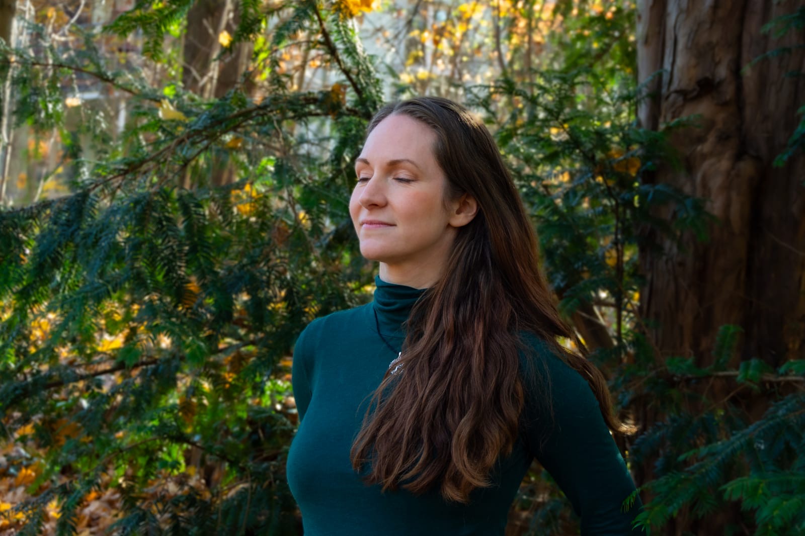 Julia Thiele steht mit geschlossenen Augen im Wald und atmet ruhig