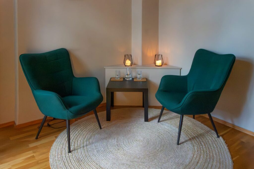Behandlungsraum im Yogahaus Dresden mit zwei grünen Sesseln und Kerzenlicht